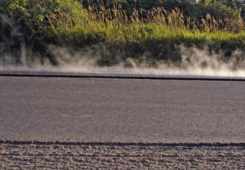 Side view of freshly paved test strip of rubber-modified hot-mix asphalt pavement for noise abatement.