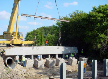 This figure is a photo of the precast pile abutment bent cap being lowered on to the steel H-piles.