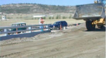 After the girders were post-tensioned together, grouted, and welded to the abutment, aggregate base course (ABC) was placed and compacted.