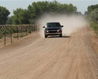 truck driving down a very dusty unpaved road