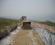 road crew applying wicking fabric to muddy section of road
