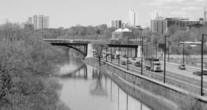 Cameo: Divided road running parallel to canal with city park on opposite side.
