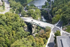 Aerial photo of the bridge crossing over the ravine and river, with a dam upstream and intersection near both ends of the bridge.