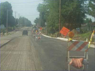Example of why all employees should wear vest. Worker on right side of barricades has a vest on. There is a worker on the left side of the barricade beside the other worker without a vest.