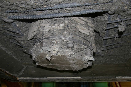 Damage to specimen SF-3 after cyclic testing has been completed, viewed from below the footing. Damage is characterized by the column punching through the footing.