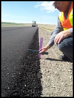 Jason Giard, an operations engineer in FHWAâ€™s Idaho Division, measures the height of a Safety EdgeSM treatment in Pocatello, Idaho.