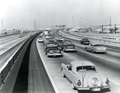 California - Traffic on the Santa Monica Freeway (I-10) near the intersection with the Santa Ana (I-105) and Golden State Freeways (I-5).  Note the use of the corrugated plastic shield on the median barrier rail.