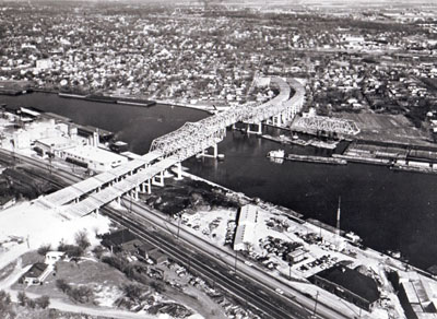 A forest of steel takes shape as twin bridges and approaches to carry Interstate Route 80 over the Des Plaines River at Joliet.  A main center span is seen here mounted on barges, ready to be floated into place.