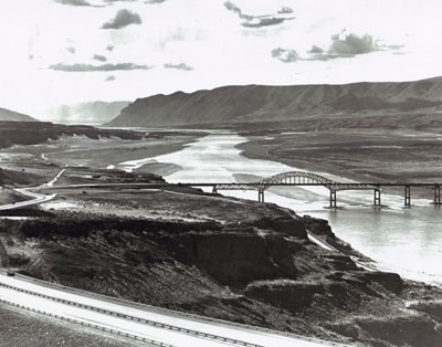 Interstate Route 90 slopes down from the foreground to cross an impressive structure over the Columbia River near Vantage, Wash.  The old bridge at this location was removed, since it would have been submerged after completion of Wanapum Dam downstream. The public utility district which built the dam contributed $4 million toward the new bridge.