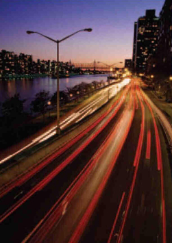 Page 2 Photograph: Time-lapse view of car tail lights and headlights moving along an expressway next to a river.