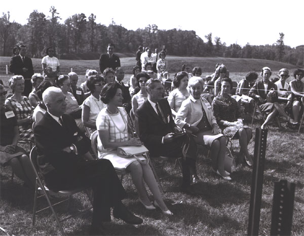 Participants in the Landscape-Landmark Tour listen to introductory remarks by Douglas B. Fugate, Chairman and Commissioner of the Virginia Department of Highways, at the Dumfries Wayside Shelter on I-95 in northern Virginia.  In front row, left to right, Virginia Governor Albertis Harrison, Lady Bird Johson, Federal Highway Administrator Rex Whitton, Muriel Humphrey, wife of Vice President Hubert H. Humphrey, and Mrs. Harrison.  