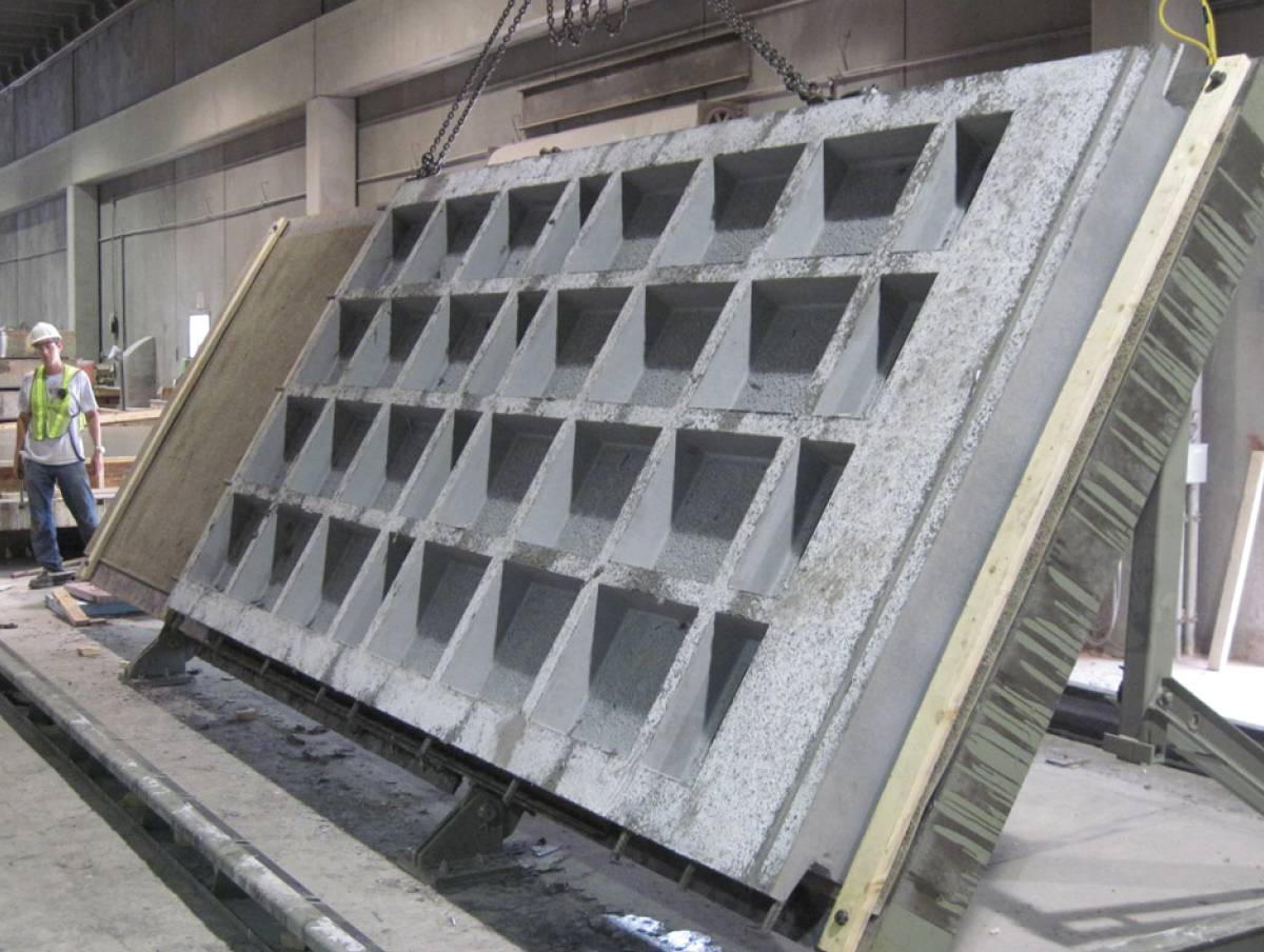 The photo depicts a waffle bridge deck panel rotated to the vertical position by the casting bed to reduce the handling stresses on the piece.