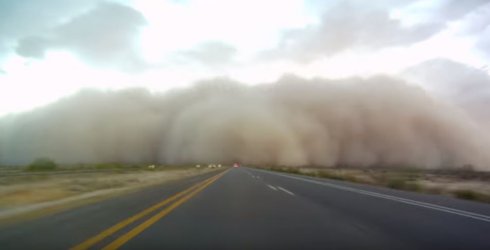 A huge dust storm streches across a road