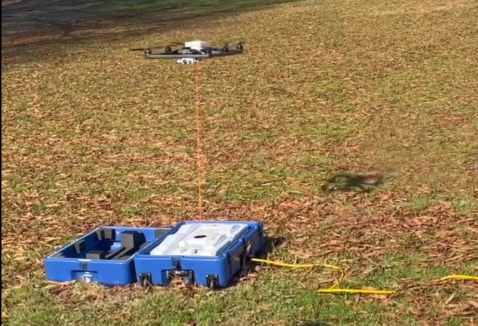 A UAS tethered to a power source hovers in the air