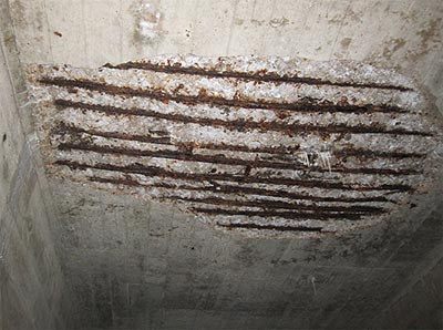 This slide shows two images identifying deterioration of the underside of the concrete deck of the Arlington Memorial Bridge. The image on the left, taken July 21, 2010, shows where the concrete has deteriorated and the concrete cover is missing, exposing corroded steel reinforcing bars. The image on the right, taken February 8, 2012, shows the same area. Additional deterioration of the concrete can be seen, as well as additional corroded metal reinforcing bars, including two reinforcing bars failed and dangling below the deck. The slide number is visible in the lower right corner.