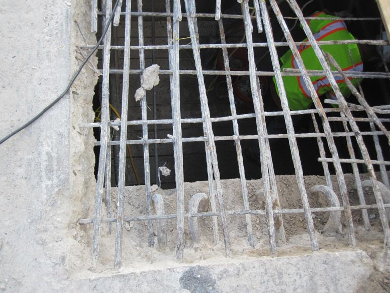 This slide shows an image of deck repairs of the Arlington Memorial Bridge taken on September 29, 2012. The image shows a large rectangular hole cut in the concrete deck. Reinforcing bars are also visible in the concrete deck, as well as the tops of curved steel stirrups from the beam below. Inside the hole is a worker wearing a bright yellow, orange, and white safety shirt. The slide number is visible in the lower right corner.