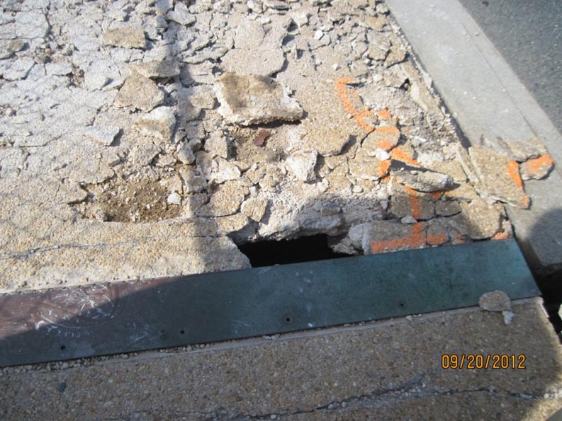 This slide shows a closeup image of the deteriorated sidewalk of the Arlington Memorial Bridge taken on September 20, 2012. The image shows thin pieces of broken concrete sidewalk just to the left of the main roadway (bridge deck). There is also a hole all the way through the sidewalk adjacent to a metal joint that connects portions of the sidewalk. The slide number is visible in the lower right corner.