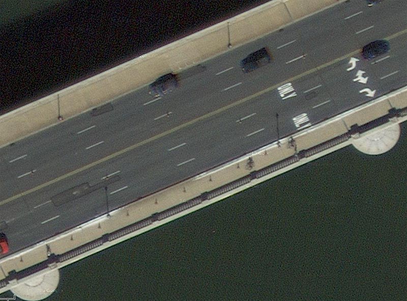This slide shows another aerial view of the six-lane bridge deck of the Arlington Memorial Bridge. There are three lanes in each direction, and there are sidewalks visible on each side of the roadway. There are light posts on the sidewalk and vehicles on the road. Also visible are the words “Only” painted on the inside far-right lane and the outside far-right lane. On each of the right lanes, arrows are painted on the surface. A left-turning arrow is painted on the inside far-right lane; a left- and right-turning arrow on the middle lane; and a right-turning arrow on the outside right lane. The slide number is visible in the lower right corner.