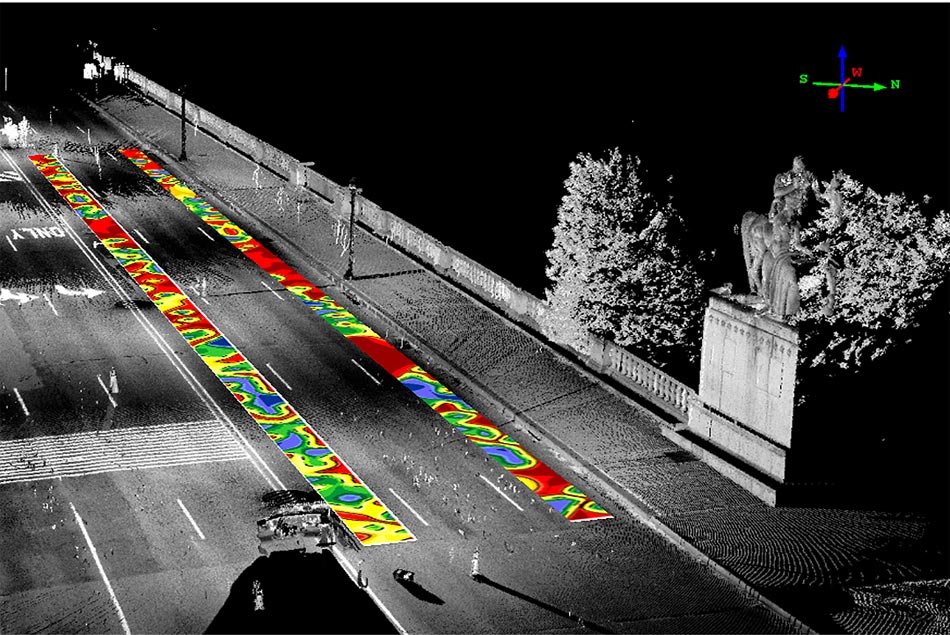 The whole slide is a black-and-white image using Light Detection and Ranging (LIDAR) of the Arlington Memorial Bridge. The image is taken looking down at the bridge from above. All six lanes of the bridge, one sidewalk, two light poles, and the bridge railing are shown. Two trees and a statue at the end of the bridge are also visible. Superimposed on top of the black-and-white LIDAR image are two colored contour plots of the Impact Echo data taken at the bridge.