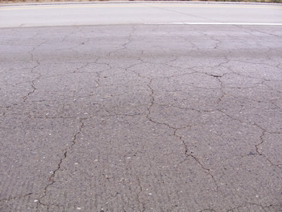 Figure 2. Photo. Map cracking in a section of pavement on Interstate 84 near Mountain Home, Idaho. This photo shows several longitudinal cracks along a concrete pavement section, with smaller cracks branching off transversely and diagonally.