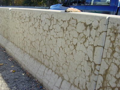 Figure 3. Photo. Concrete barriers along Route 2 near Leominster, Massachusetts. This photo shows several horizontal cracks along two sections of concrete barriers, and the cracks are connected by several vertical cracks.