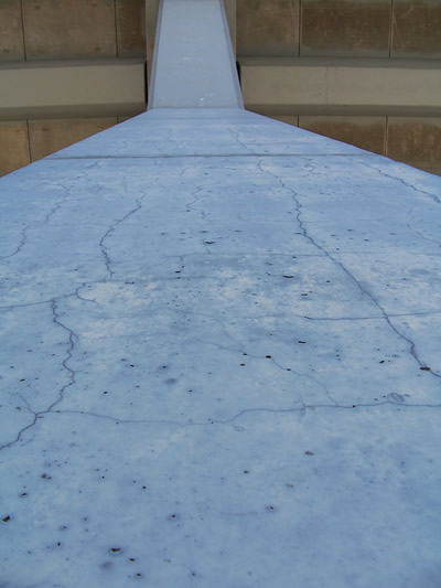 Figure 5. Photo. ASR affected column in Houston, Texas. This photo shows a close view of an ASR affected concrete column in Houston, Texas. Cracks are evident in the vertical direction, with popouts along the surface of the side of the column.