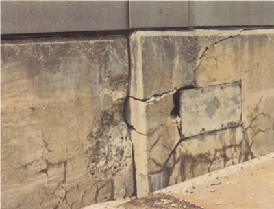 Figure 6. Photo. Misalignment of adjacent sections of a parapet wall on a highway bridge due to ASR-induced expansion. This figure shows the misalignment of adjacent sections of a parapet wall on a highway bridge. Although there is no scale, the lateral misalignment could be on the order of several centimeters. Both sections contain horizontal and vertical cracks.