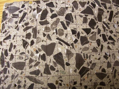 This figure shows a close-up of a polished concrete sample. A grid with several squares has been labeled with a marker for the evaluation.