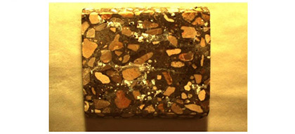 This picture (located in the center below the other two photos) shows a polished concrete sample. Specks of white paste are visible on various areas of the surface of the specimen.