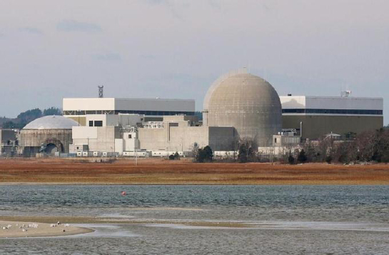 This image shows the Seabrook Station Nuclear Power Plant. Various structures including buildings and domes make up the facility. A pond is seen in the foreground.