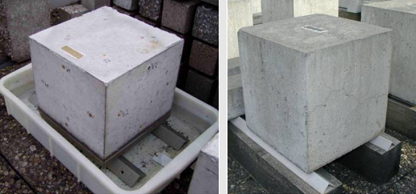 This image shows two concrete cubes at outdoor exposure sites. One cube is partially submerged in a shallow tub of water.