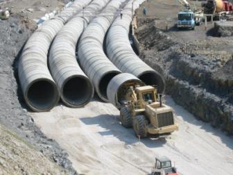 Four 120-inch reinforced concrete pipes being placed.