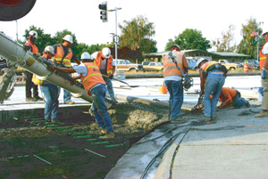 Workers on a road construction project pouring concrete