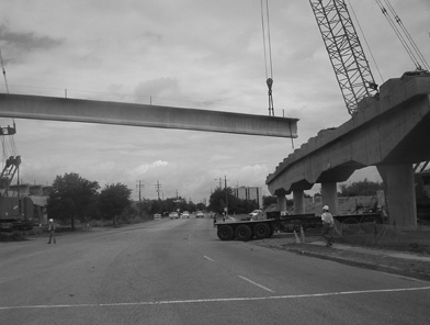 A large concrete girder being lifted and put in place