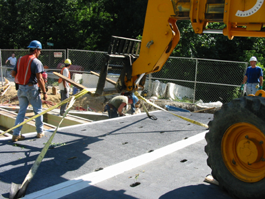 Workers replacing deck on a steel through-truss bridge