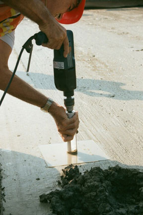 A concrete sample for air void analyzer testing is obtained using a vibrating drill.