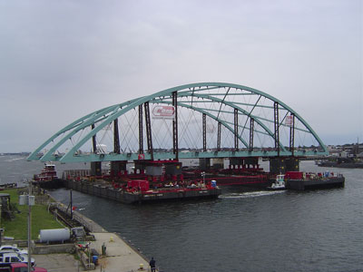 Figure 7. Photo. The prefabricated superstructure for Rhode Island's Providence River bridge is transported on two barges to the bridge site.