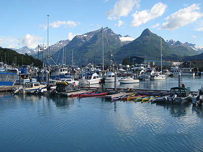 A view of Alaska's Valdez harbor. Boats can be seen in the harbor and mountains are in the background.