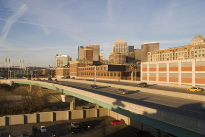 Photo. A shot of Fort Washington Way, which travels through Cincinnati, OH. Cars are visible on the roadway. In the background is Cincinnati's skyline.