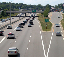 Figure 8. Photo. A view of a highway with HOV or HOT lanes, three standard lanes in both directions, and an exit ramp. Traffic flows in both directions.