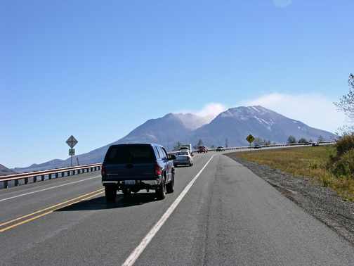 Figure 3. Photo. Traffic travels on a two-lane mountain road in Washington State.