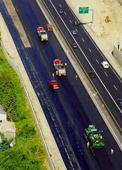 Figure 6. Photo. An aerial view of a four-lane highway. Two lanes are closed for rehabilitation work, with trucks and maintenance personnel visible in the closed lanes.