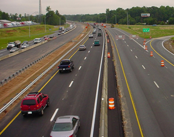 Figure 9. Photo. Traffic travels on a multi-lane highway. To the right of the traffic, two lanes of the highway are closed off for road work.