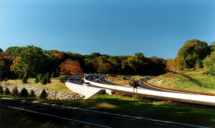 Figure 5. Photo. A view of a scenic four-lane roadway with traffic traveling on it. A wooded area can be seen in the background.