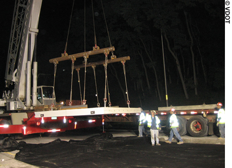 A crane lifts precast, prestressed concrete panels in preparation for installing them overnight on I-66 in Fairfax County, VA. Four construction workers are visible.