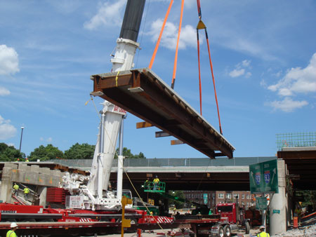 A close-up of part of the bridge superstructure being lifted by a crane.