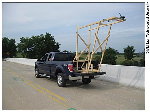 Photo of a camera mounted on the flatbed of a pickup truck driving on a bridge deck.