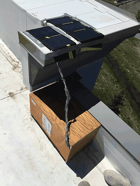 Photo: The control system that collects, processes, and transmits the real-time water quality data collected by in situ sensors. A wooden rectangular box has a wire running from the top of it. The box is placed on the roof of a building in Bozeman, MT.
