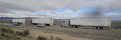 Photo of three trucks traveling behind each other on an open road in an automated truck platoon. Dedicated short range communication is used between the lead and following vehicles for increased capacity and improved fuel efficiency.