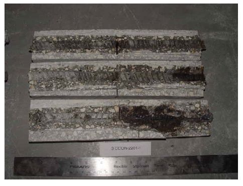 Corrosion products are present where the simulated crack intersected the bars, and in one case the buildup of products is extensive to one side of the crack trace.